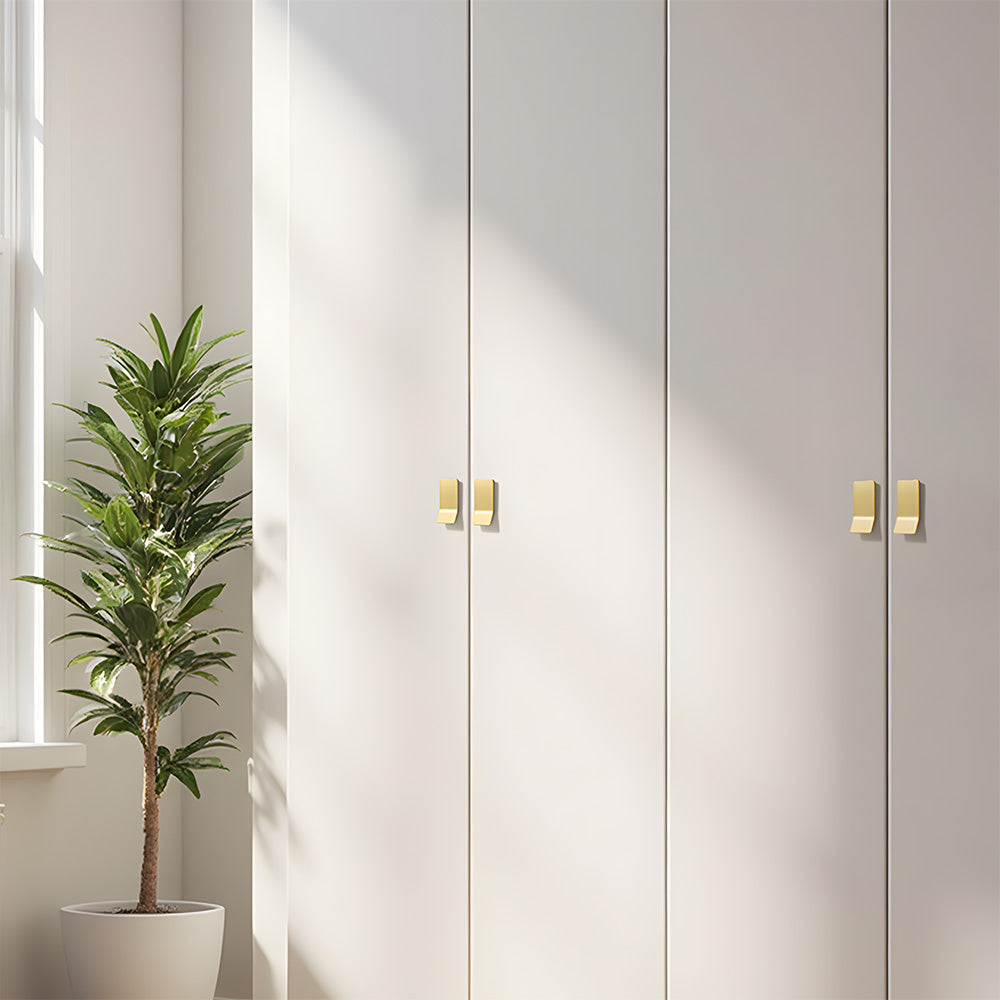 Gold square finger edge pull with a curved grip, shown clearly installed on cabinetry in context