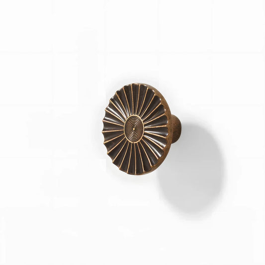 Sunburst half-moon cabinet pull and round knob, shown from one angle on a clean neutral background