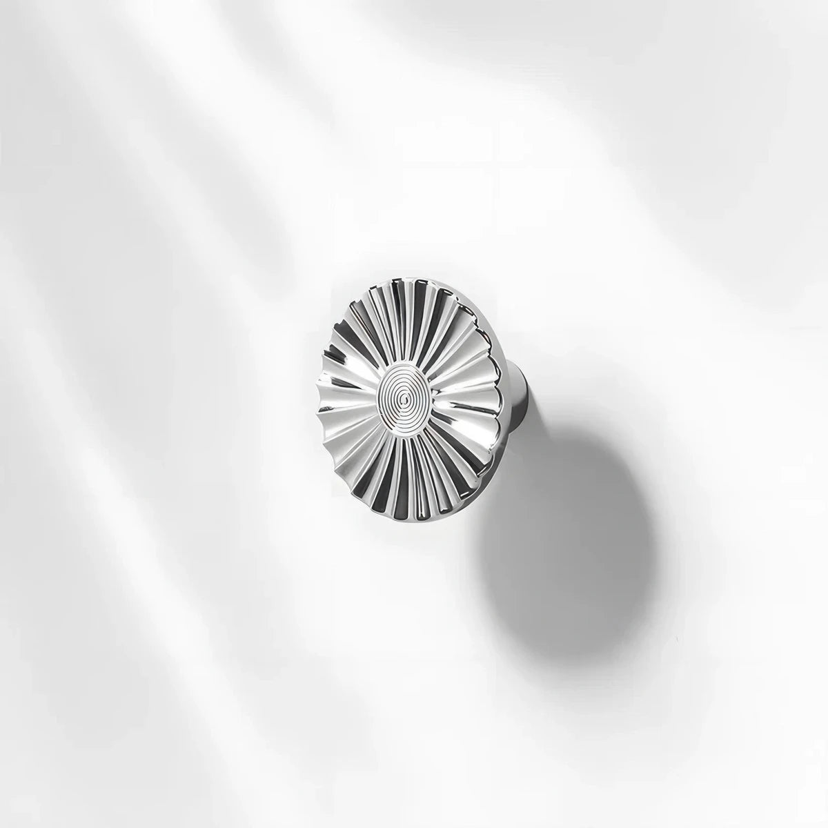 Silver sunburst half-moon cabinet pull and round knob, shown clearly with its shape and finish visible