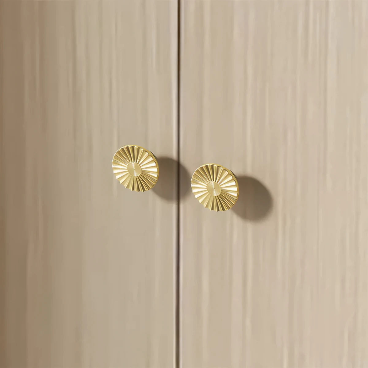 Sunburst half-moon cabinet pull and round knob, shown from one angle installed on cabinetry in context