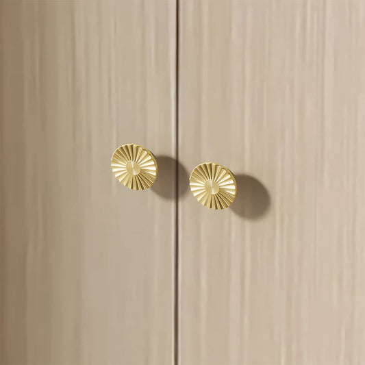 Sunburst half-moon cabinet pull and round knob, shown from one angle installed on cabinetry in context