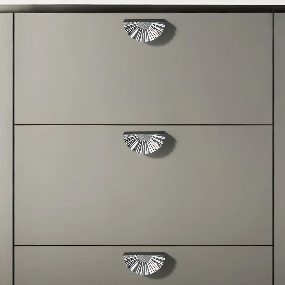 Silver sunburst half-moon cabinet pull and round knob, presented for reference installed on cabinetry in context