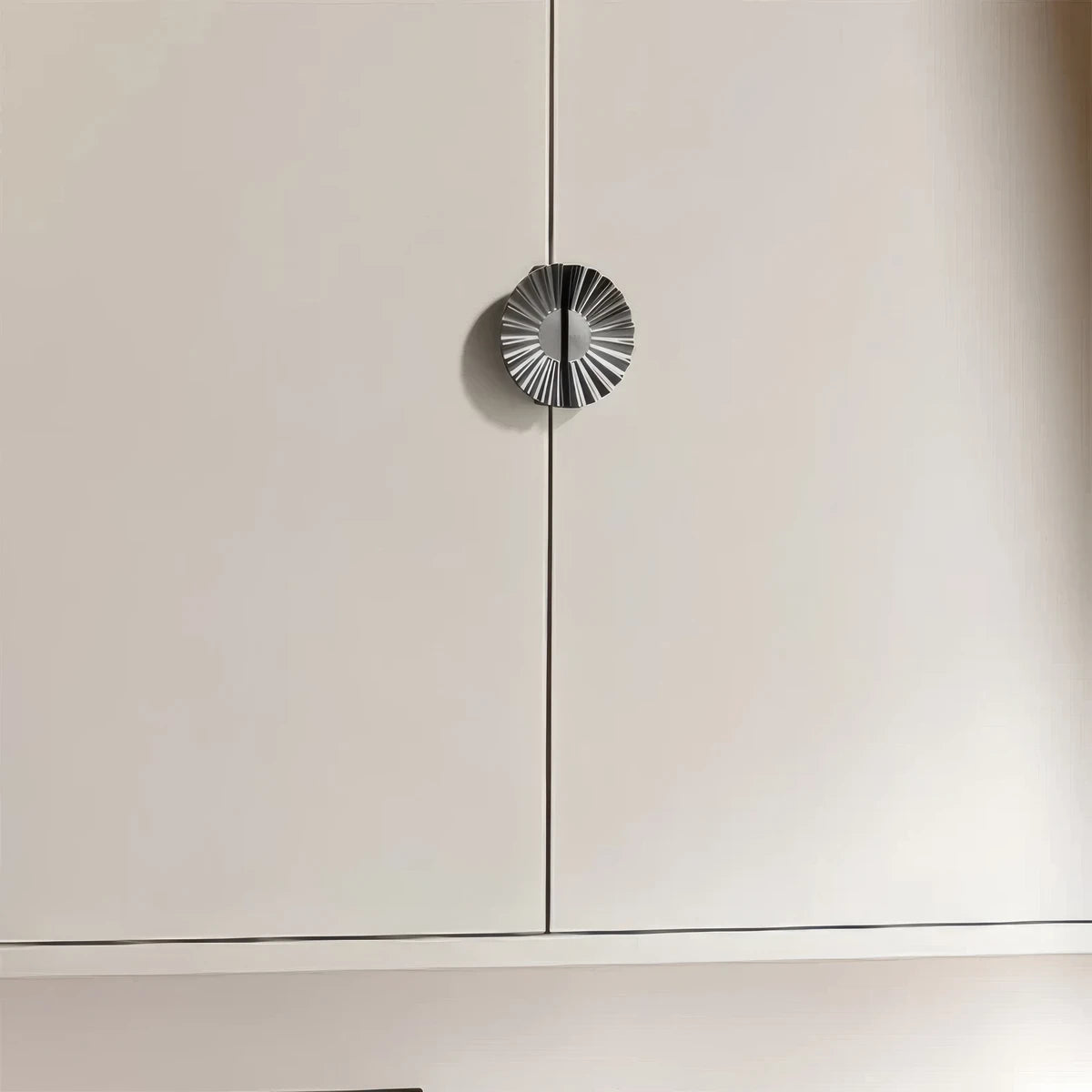 Sunburst half-moon cabinet pull and round knob, shown at close range installed on cabinetry in context