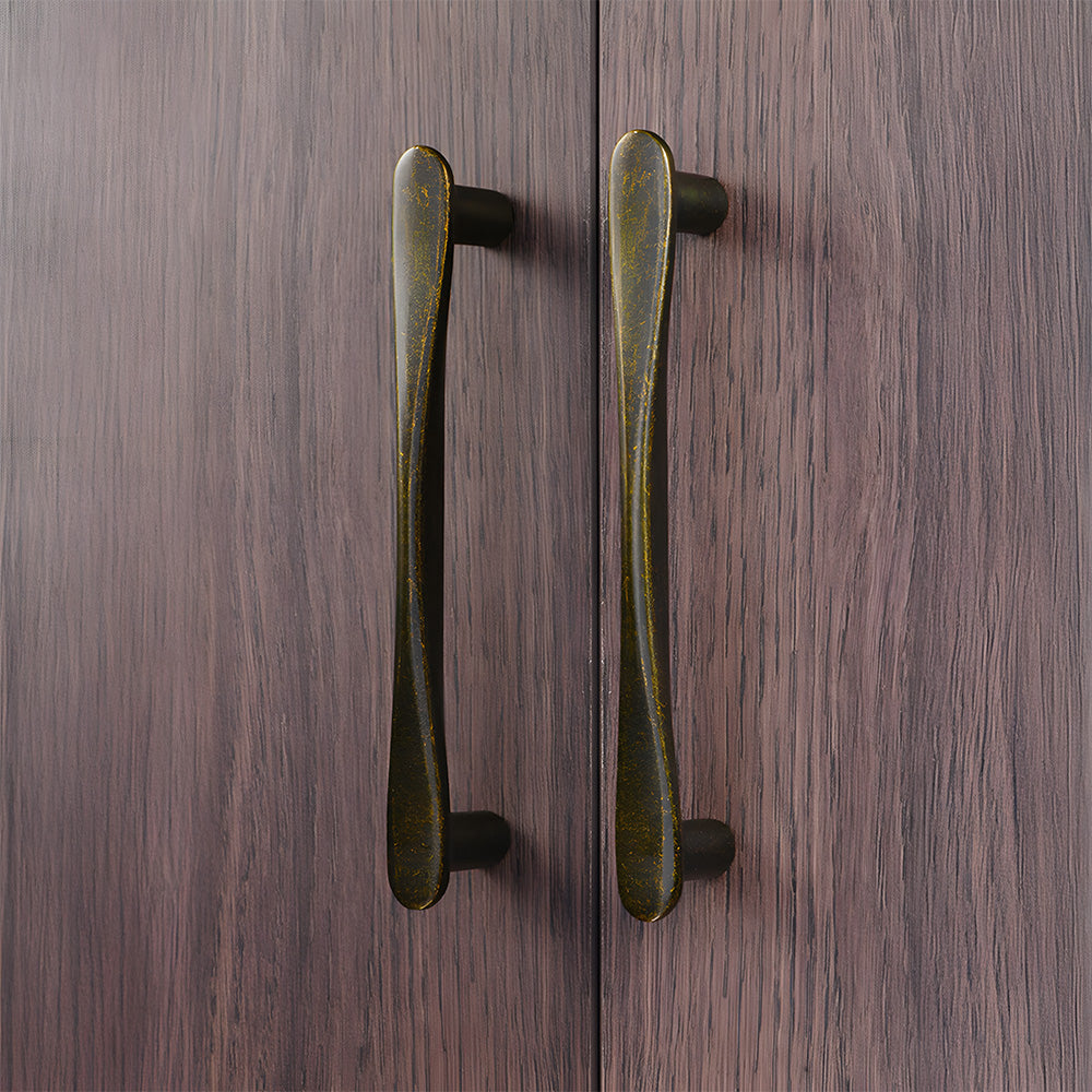Antique bronze tapered arched brass cabinet pull, pictured in one view in an installed cabinet close-up