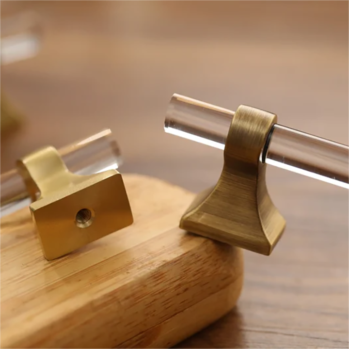 Transparent acrylic bar pull with flared metal mounts, shown at close range with its construction and finish visible