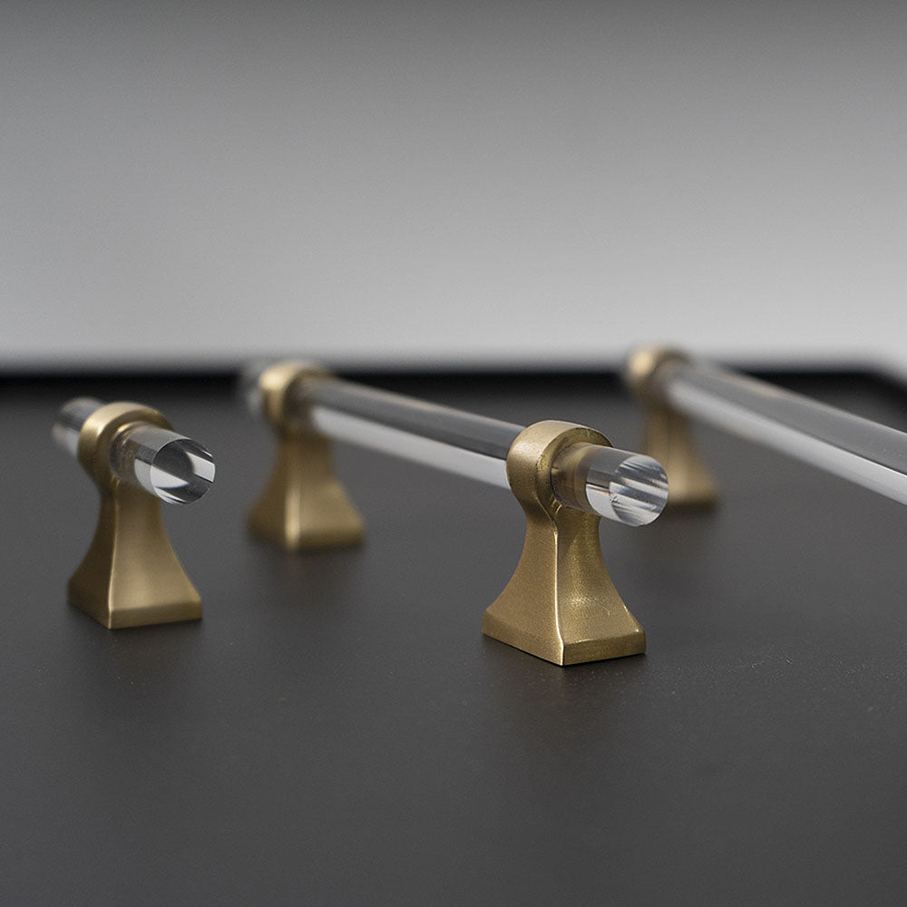 Transparent acrylic bar pull with flared metal mounts, shown from one angle with its construction and finish visible