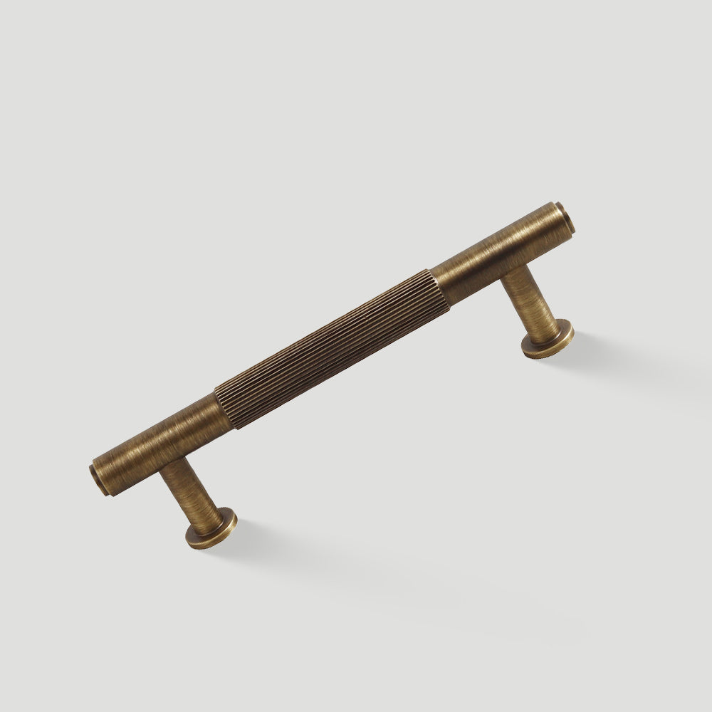 Lined aged-bronze brass T-bar cabinet pull and knob, shown clearly on a clean neutral background