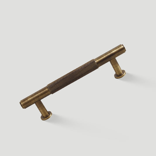 Lined aged-bronze brass T-bar cabinet pull and knob, shown clearly on a clean neutral background
