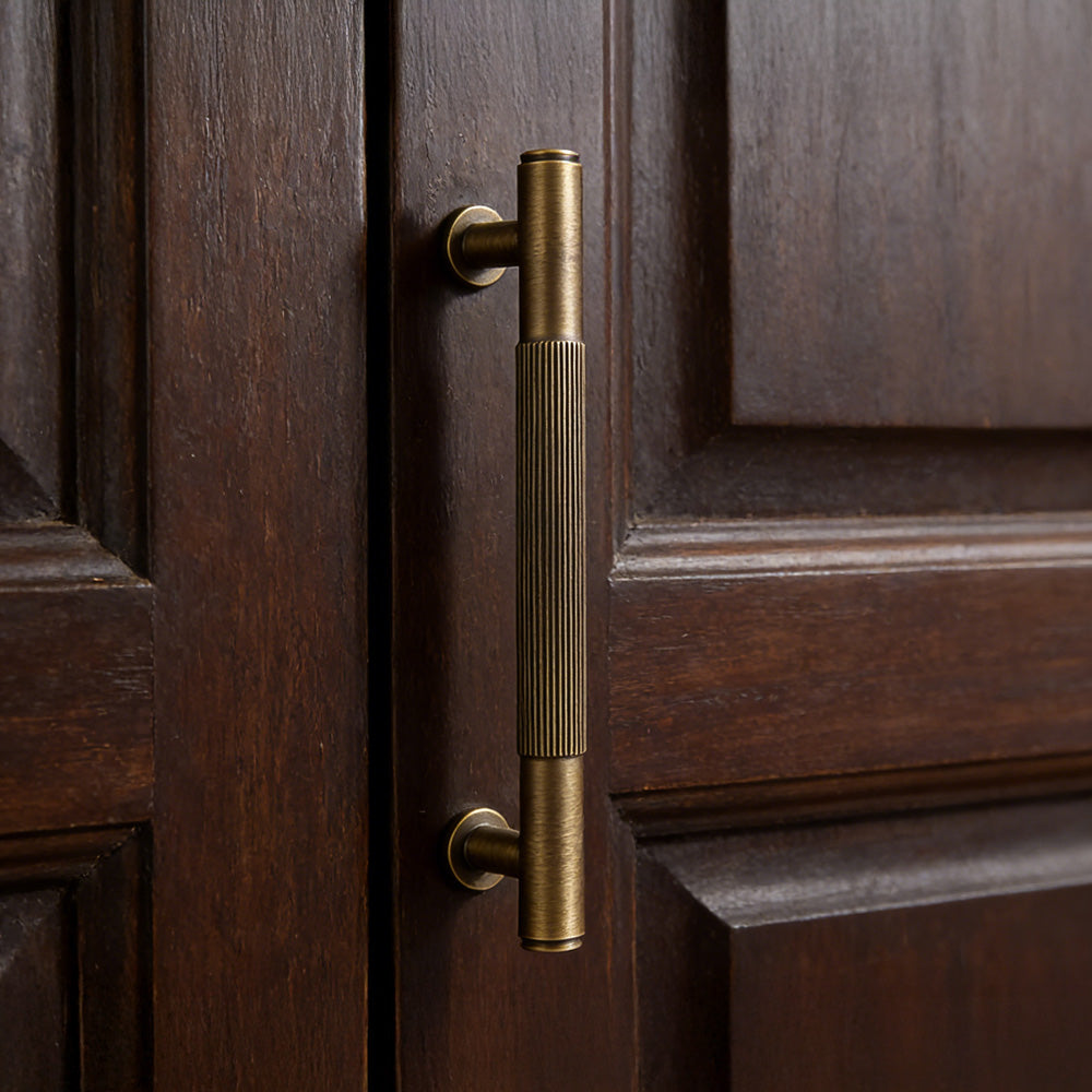 Lined aged-bronze brass T-bar cabinet pull and knob, pictured in one view in an installed cabinet close-up