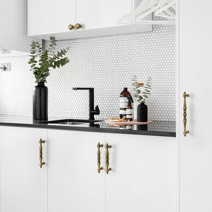 Bronze vintage turned brass cabinet pull and round knob, shown at close range installed on cabinetry in context