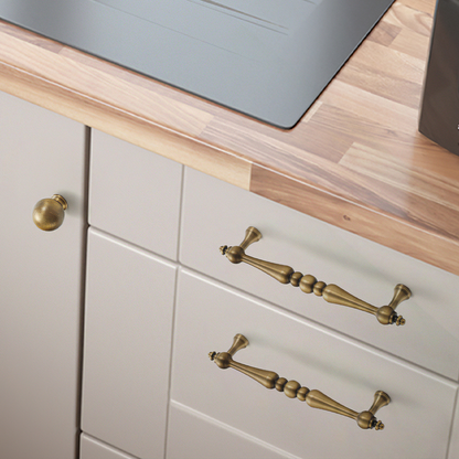 Bronze vintage turned brass cabinet pull and round knob, displayed from the side installed on cabinetry in context