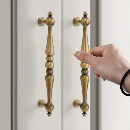 Bronze vintage turned brass cabinet pull and round knob, shown from one angle while held or operated by hand
