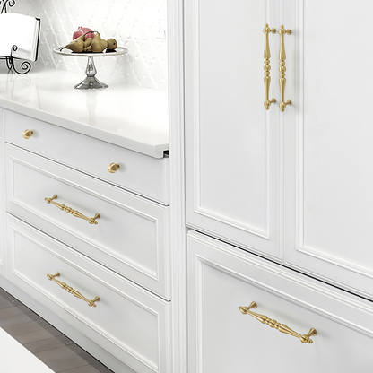 Gold vintage turned brass cabinet pull and round knob, shown from one angle installed on cabinetry in context