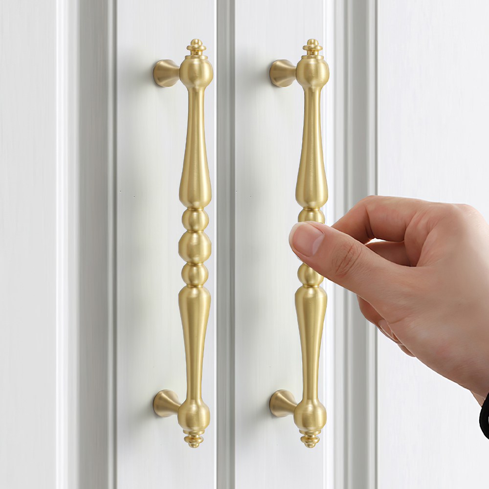 Gold vintage turned brass cabinet pull and round knob, shown clearly while held or operated by hand