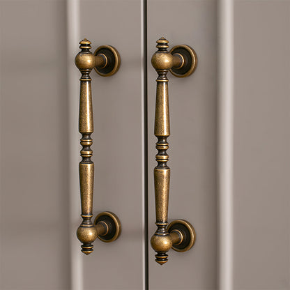 Bronze vintage turned brass cabinet pull and round knob, shown from one angle installed on cabinetry in context