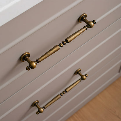 Vintage turned brass cabinet pull and round knob, pictured in one view installed on cabinetry in context