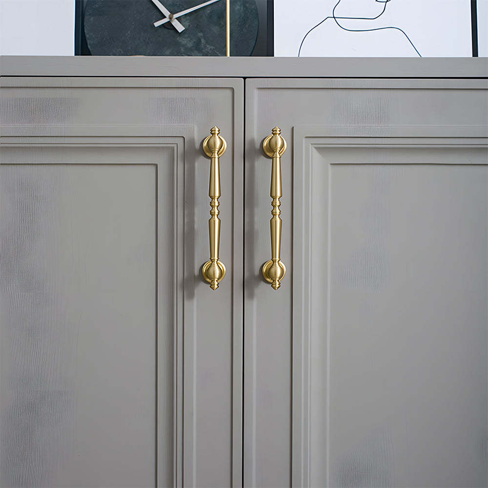 Gold vintage turned brass cabinet pull and round knob, shown clearly mounted on a finished cabinet front
