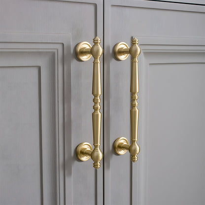 Gold vintage turned brass cabinet pull and round knob, pictured in one view mounted on a finished cabinet front