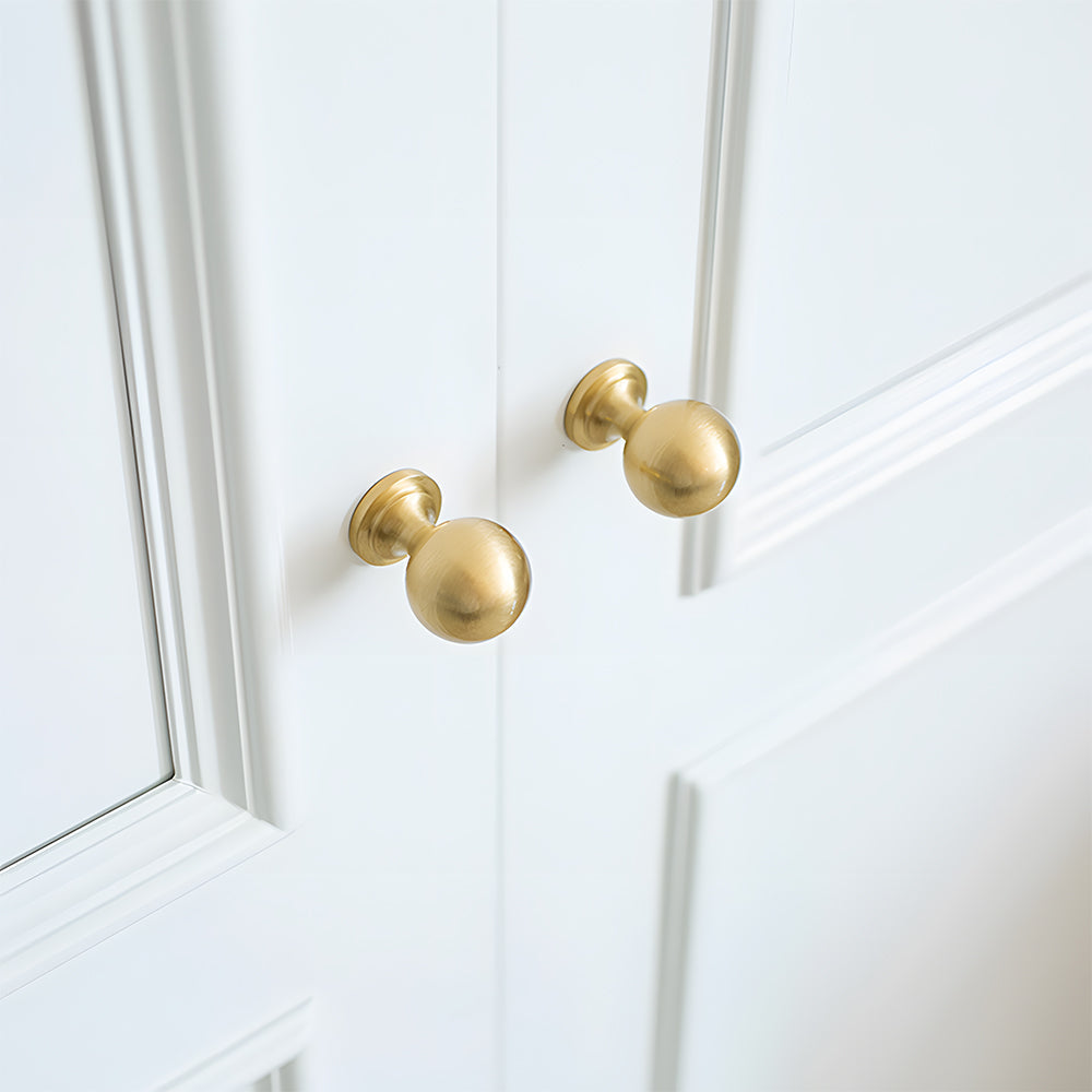 Gold vintage turned brass cabinet pull and round knob, presented for reference mounted on a finished cabinet front
