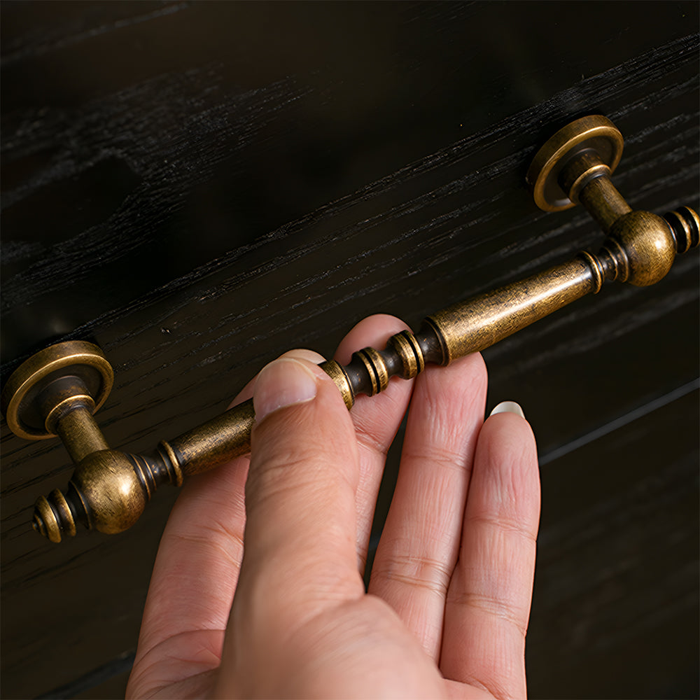Vintage turned brass cabinet pull and round knob, shown clearly while held or operated by hand