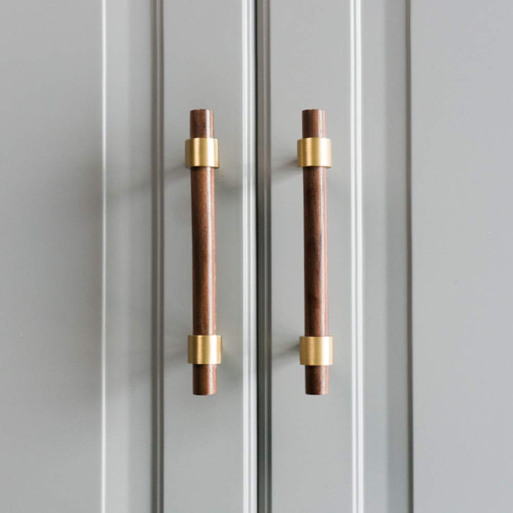 Walnut or beech wood cabinet pull with brushed brass bases, installed on paired cabinet doors in a close view