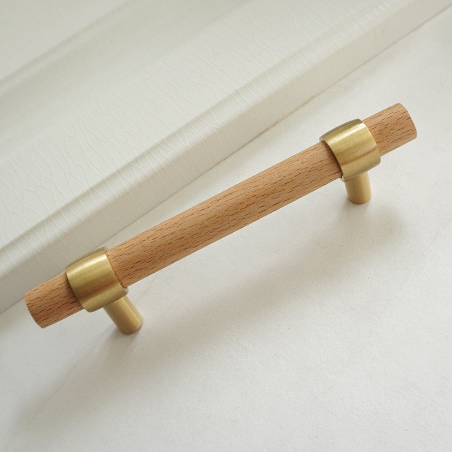 Wood cabinet pull with brass bases in beech, shown as a single product on a white background