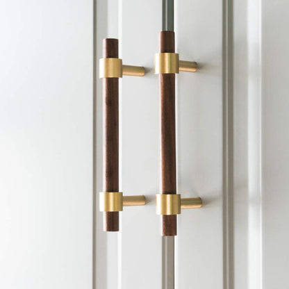 Walnut or beech wood cabinet pull with brushed brass bases, mounted as matching hardware on double cabinet doors