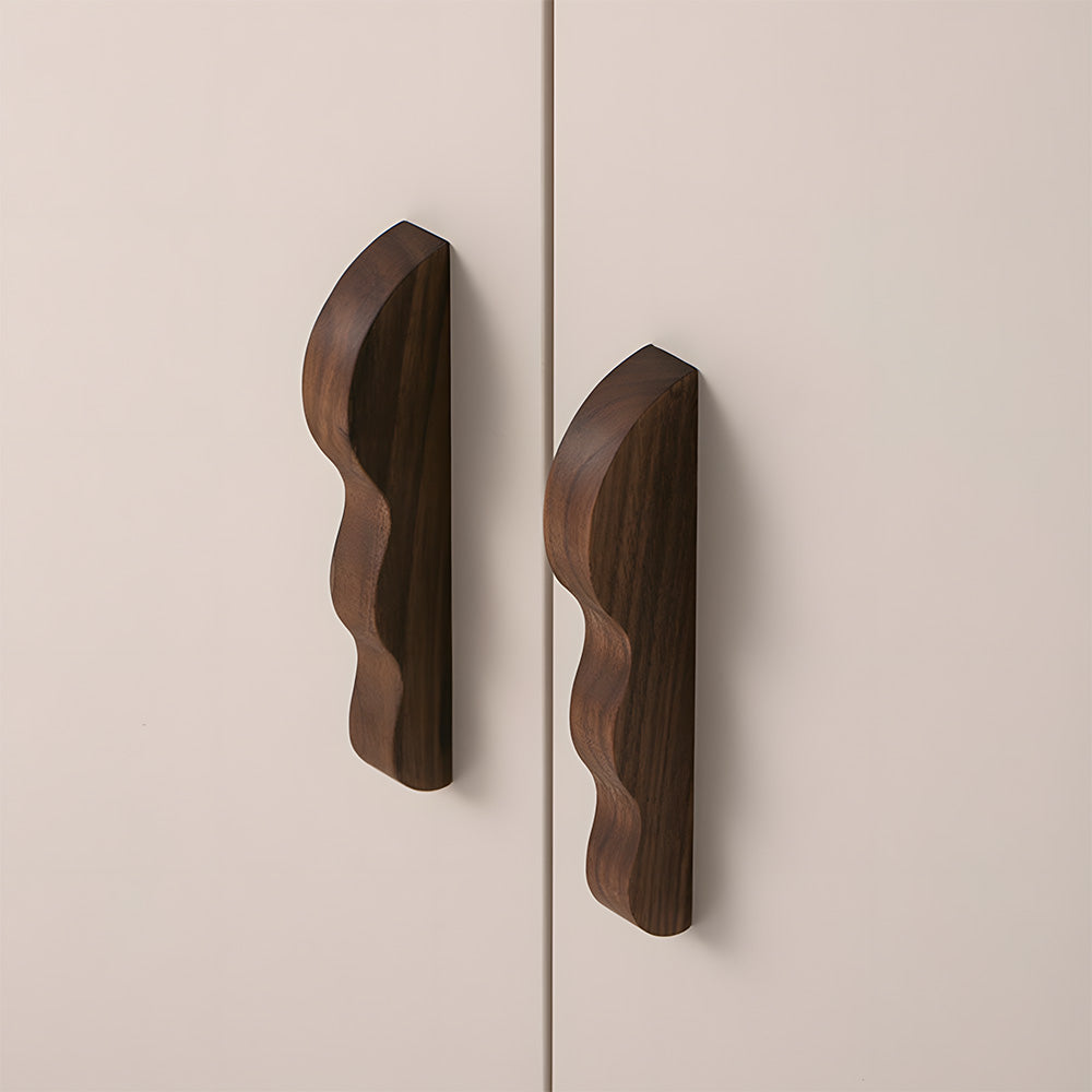 Wavy wood cabinet pull with a sculpted three-curve profile, shown in a close installed view across cabinet fronts