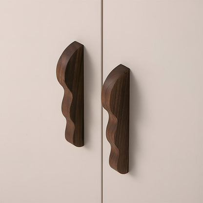 Wavy wood cabinet pull with a sculpted three-curve profile, shown in a close installed view across cabinet fronts
