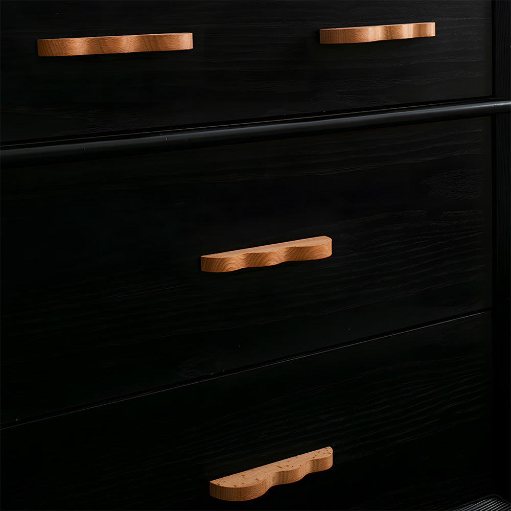 Wavy wood cabinet pull with a sculpted three-curve profile, shown across several drawer fronts in a cabinet scene