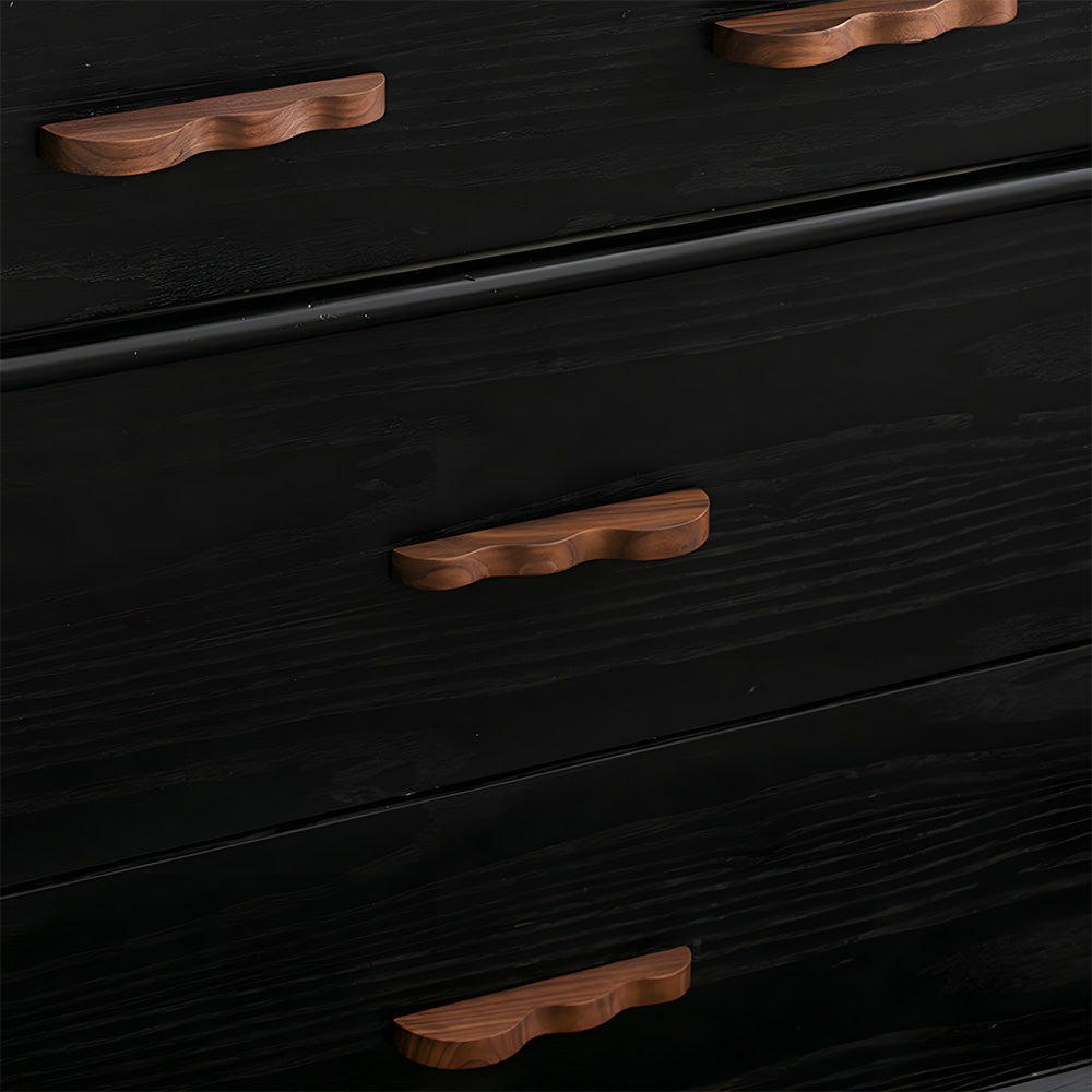 Wavy wood cabinet pull with a sculpted three-curve profile, installed on drawer fronts in a bright room setting