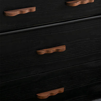 Wavy wood cabinet pull with a sculpted three-curve profile, installed on drawer fronts in a bright room setting