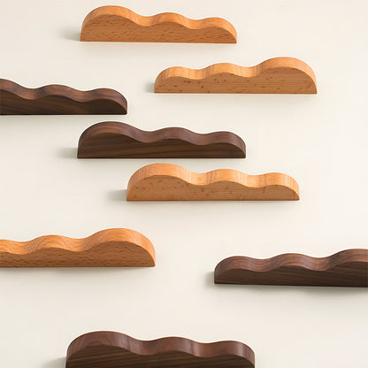 Wavy wood cabinet pull with a sculpted three-curve profile, grouped on a light surface to compare lengths and profiles