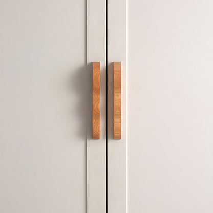 Wavy wood cabinet pull with a sculpted three-curve profile, installed on paired cabinet doors in a close view