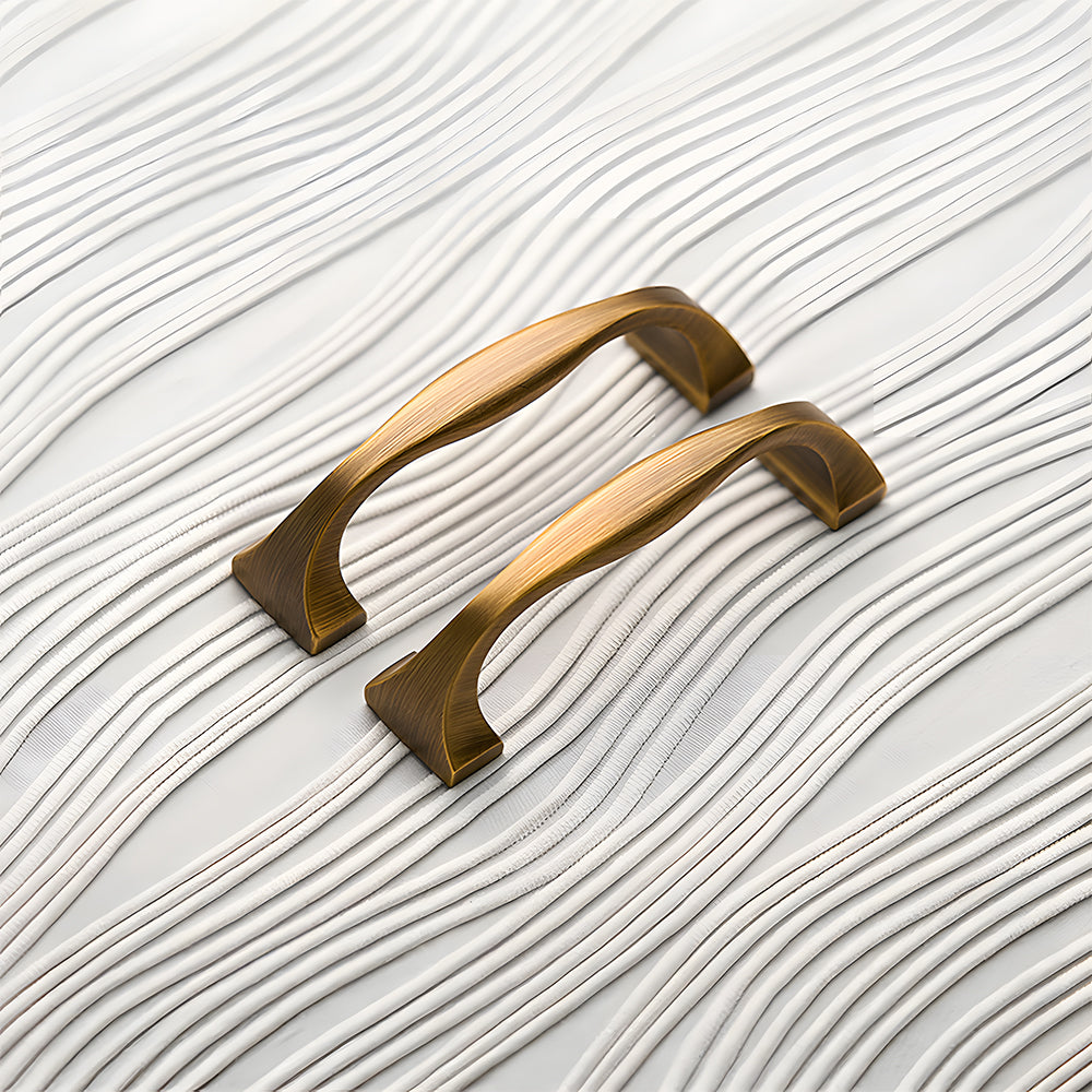 Wide arched brass cabinet pull with flared square ends, shown clearly as a color and finish lineup