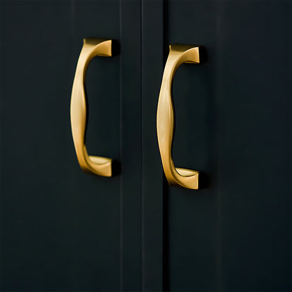 Wide arched brass cabinet pull with flared square ends, presented in another view installed on cabinetry in context
