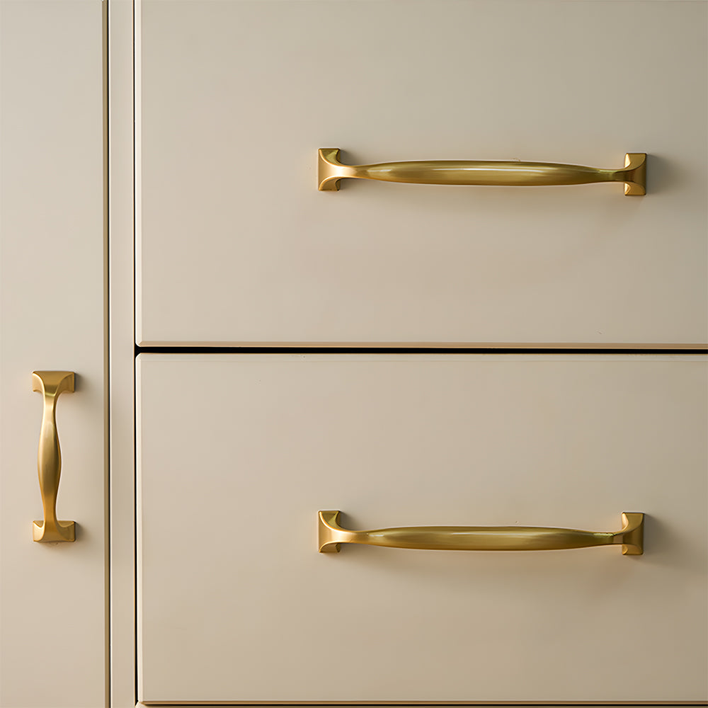 Wide arched brass cabinet pull with flared square ends, shown from one angle mounted on a finished cabinet front