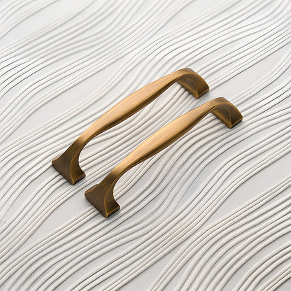 Wide arched brass cabinet pull with flared square ends, shown from one angle as a color and finish lineup
