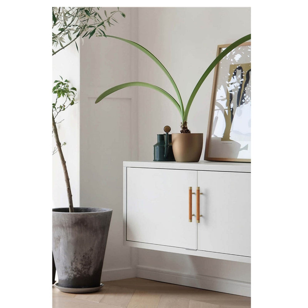 Light wood cabinet handle with brushed brass end caps, mounted as matching hardware on double cabinet doors