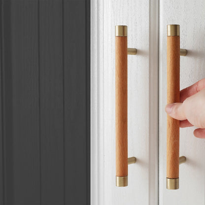 Wood cabinet handle with brass end caps, installed on paired cabinet doors in a close view