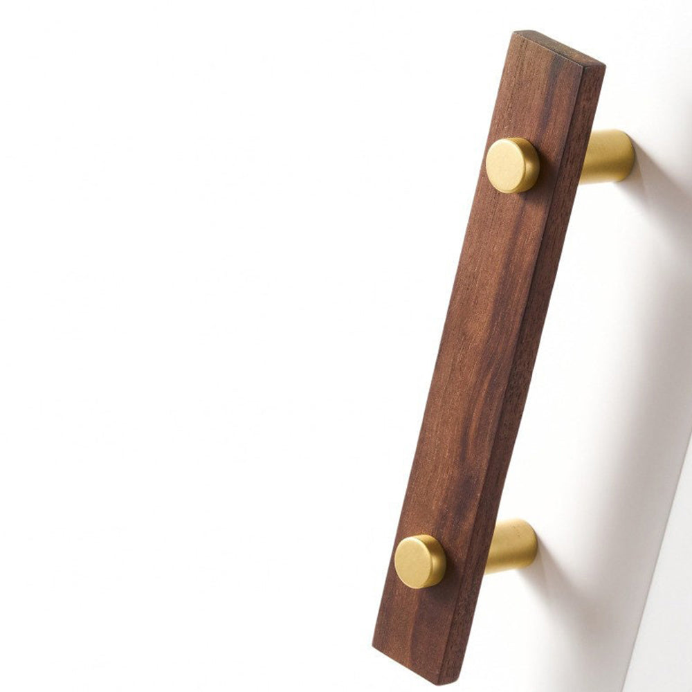 Wood-grain cabinet pull with metal posts in light wood with gold posts, shown on cabinet fronts in a bright room setting