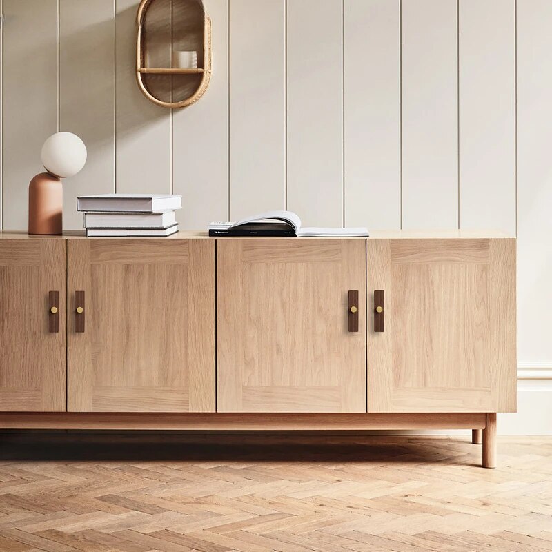 Wood-grain cabinet pull with round black or gold metal posts, installed on paired cabinet doors in a close view