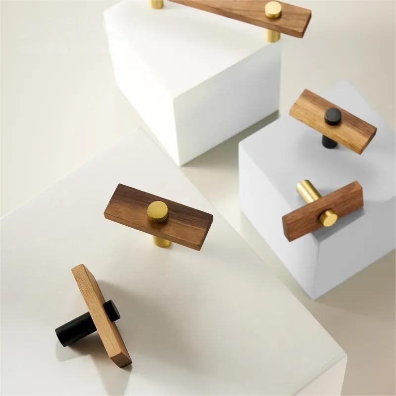 Wood-grain cabinet pull with round black or gold metal posts, shown as a mixed lineup of related hardware pieces