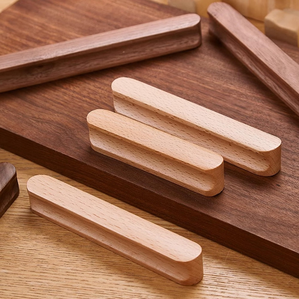 Rounded wood cabinet pull in light wood with 64 mm centers, arranged together from an overhead angle for comparison