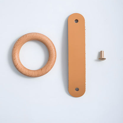 Disassembled wood ring cabinet knob with leather strap and mounting screw beside the wood ring