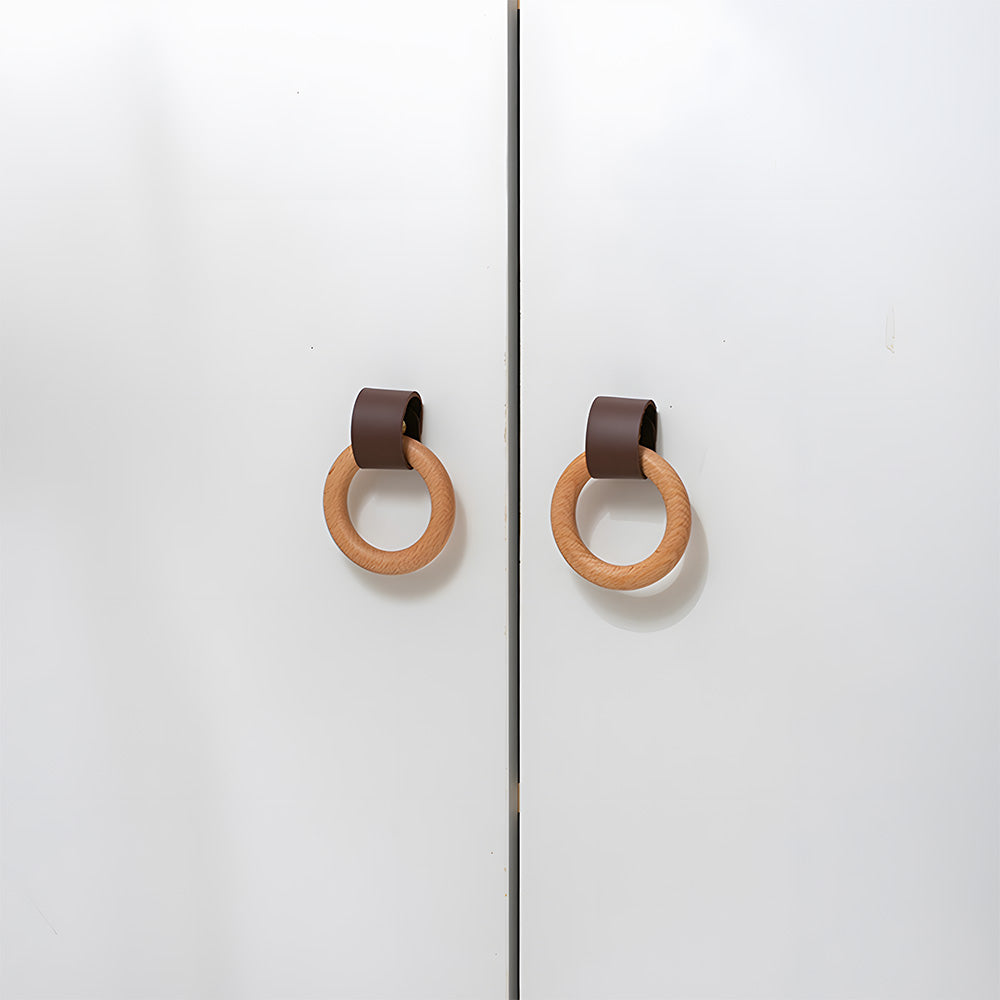 Two brown leather and wood ring cabinet knobs installed on paired white cabinet doors