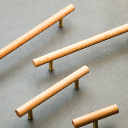Wood cabinet pull with brass posts in light wood, arranged together from an overhead angle for comparison