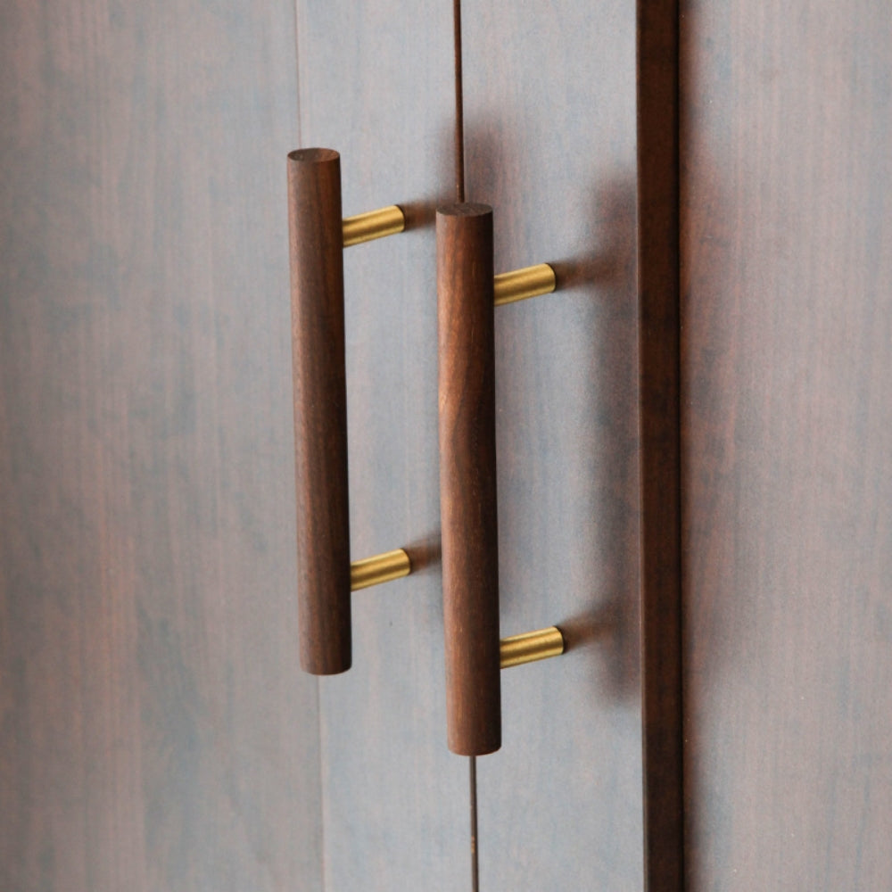 Wood cabinet pull with brass posts in brown with 96 mm centers, mounted on tall cabinet doors in a wider room view