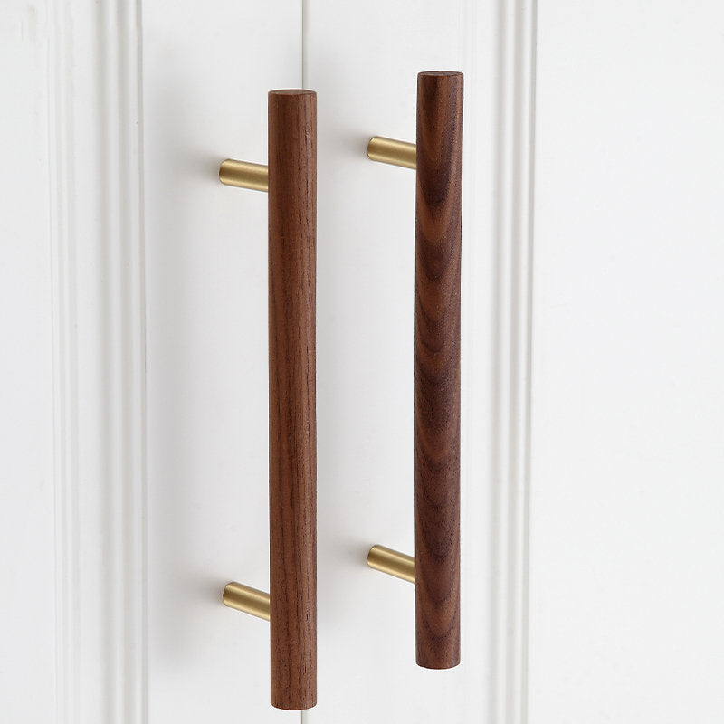 Wood and brass cabinet pull with a round bar profile, installed on paired cabinet doors in a close view