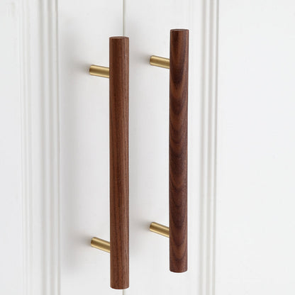 Wood and brass cabinet pull with a round bar profile, installed on paired cabinet doors in a close view